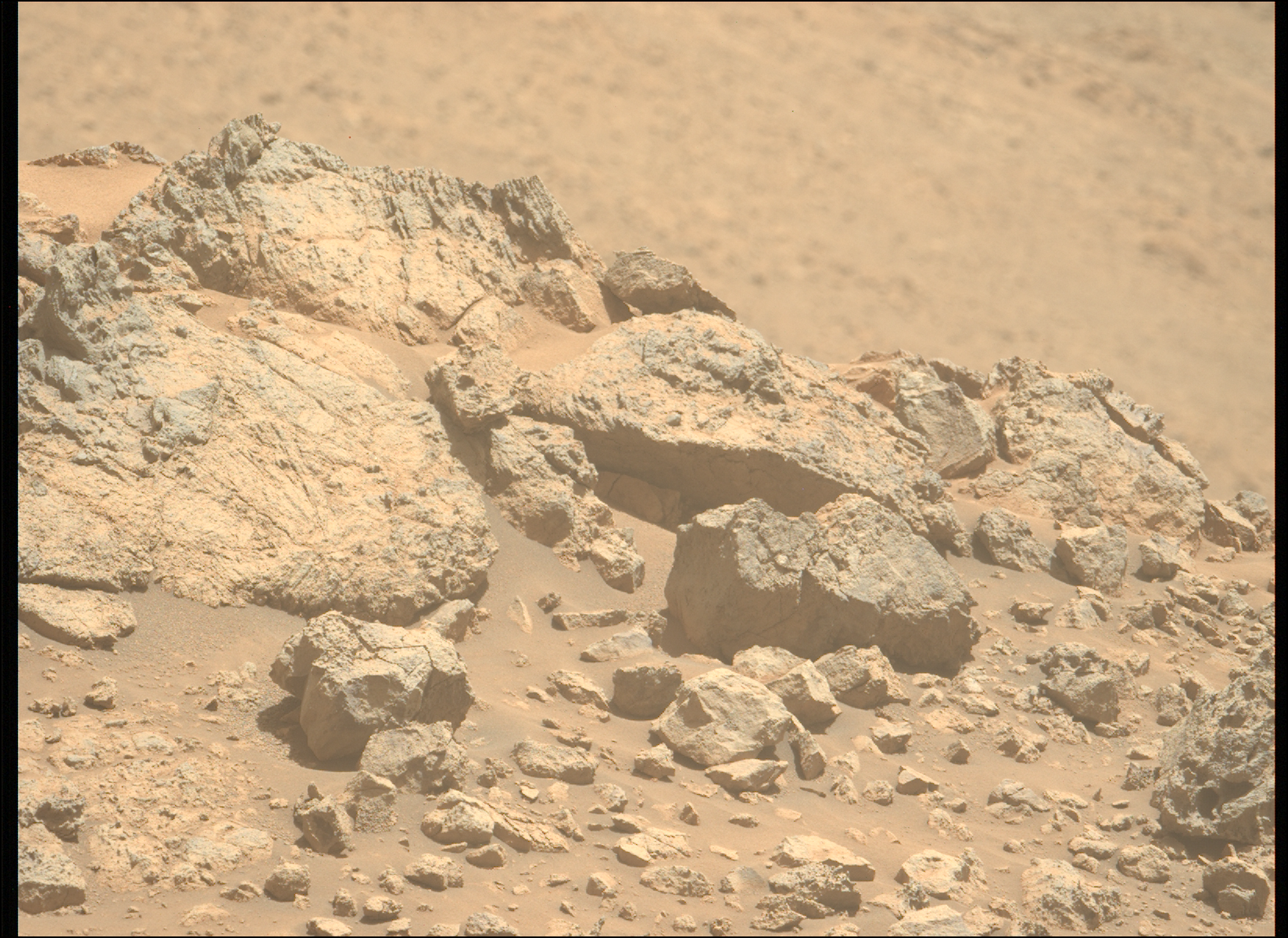 mars perseverance zl0 1452 0795840021 894eby n0700228zcam09510 1100lmj.png A color photo from the Martian surface shows pale orange, very rocky terrain in the foreground, taking up the lower two-thirds of the frame, creating a horizon line from the upper left corner of the image to the middle right side. The terrain beyond, in the distance, is blurry and takes up the rest of the frame. The rocks in the foreground range from tiny, sharp stones to large outcroppings, the latter showing some medium gray highlights among the orange rock and dust that comprise them. The largest rocks, on the left side, show numerous grooves and cracks on their faces, ranging from vertical to slightly left-skewing.