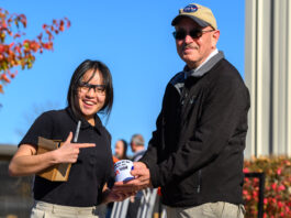 NASA and Notre Dame Unite to Encourage STEM Career Aspirations Portage School of Leaders High School junior Rebecca Anderson, wearing a black short-sleeved shirt and glasses, stands smiling beside NASA Glenn’s Daniel Sutliff, an acoustic engineer, on the campus of the University of Notre Dame. Sutliff is wearing a NASA ballcap and black jacket. He and Anderson are holding an autographed NASA mug, which Sutliff signed with a black ink permanent magic marker. Anderson is holding the black marker and a small cardboard box.