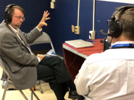 Keith Koehler: Wallops’ News Chief Excels in Leadership and Communication Keith Koehler, a white man with short brown hair and beard, sits in a chair and gestures with one hand while doing a radio interview. He wears headphones, a taupe jacket, and dark pants.