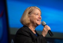 NASA Leaders Visit Mexico to Enhance Collaborative Efforts NASA Deputy Administrator Pam Melroy smiles as she speaks into a microphone at an employee town hall, with a blue background behind her.