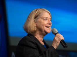 NASA Leaders Visit Mexico to Enhance Collaborative Efforts NASA Deputy Administrator Pam Melroy smiles as she speaks into a microphone at an employee town hall, with a blue background behind her.