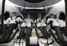 SpaceX Crew-8 Returns to Earth with Florida Splashdown The four NASA SpaceX Crew-8 members sit in a row, smiling and waving in their spacesuits aboard a Dragon spacecraft.