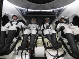 SpaceX Crew-8 Returns to Earth with Florida Splashdown The four NASA SpaceX Crew-8 members sit in a row, smiling and waving in their spacesuits aboard a Dragon spacecraft.