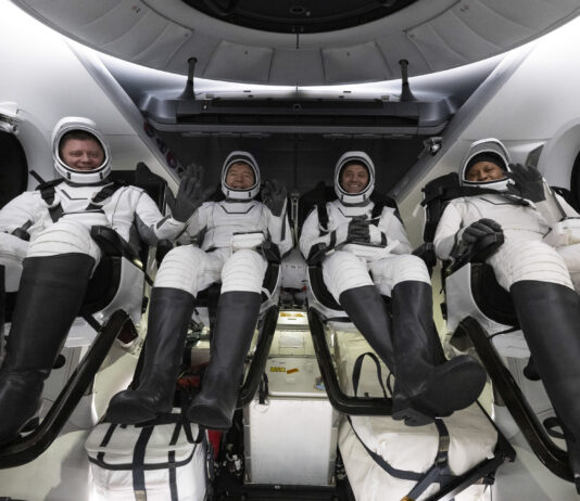SpaceX Crew-8 Returns to Earth with Florida Splashdown The four NASA SpaceX Crew-8 members sit in a row, smiling and waving in their spacesuits aboard a Dragon spacecraft.