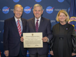 Ex-NASA Astronaut Bob Cabana Honored with Prestigious Civilian Award Nelson, Cabana, and Melroy are side by side, smiling, in front of a background with NASA logos, with Cabana holding the award certificate.