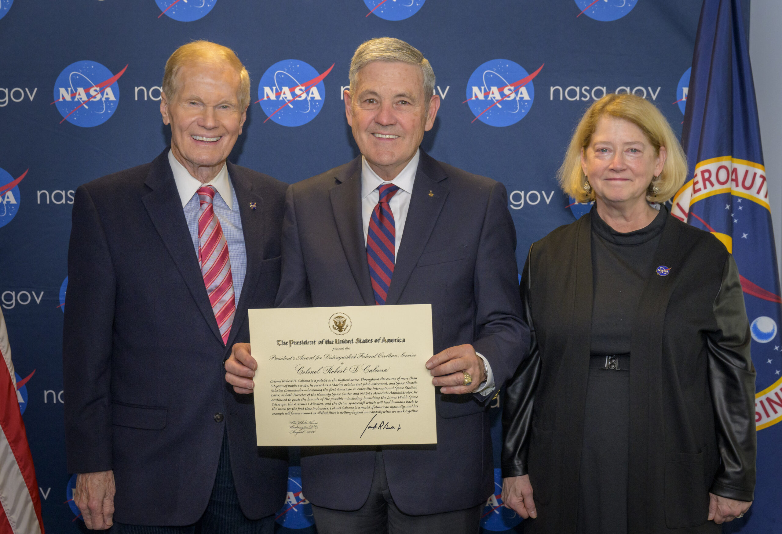 nhq202501100001 2k.jpg Nelson, Cabana, and Melroy are side by side, smiling, in front of a background with NASA logos, with Cabana holding the award certificate.