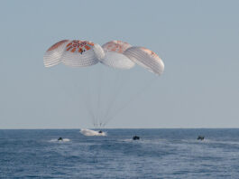 NASA’s SpaceX Crew-9 Returns to Earth from Science Mission Four large white and red parachutes are fully deployed above a SpaceX Dragon spacecraft splashing into the water.