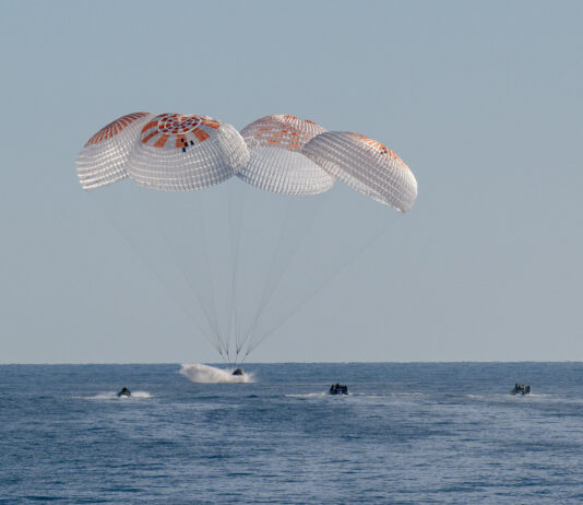 NASA’s SpaceX Crew-9 Returns to Earth from Science Mission Four large white and red parachutes are fully deployed above a SpaceX Dragon spacecraft splashing into the water.