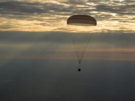 NASA Announces Broadcast for Astronaut Jonny Kim’s Crew Return The photo features a dim horizon with the Soyuz MS-26 spacecraft as it lands by parachute.
