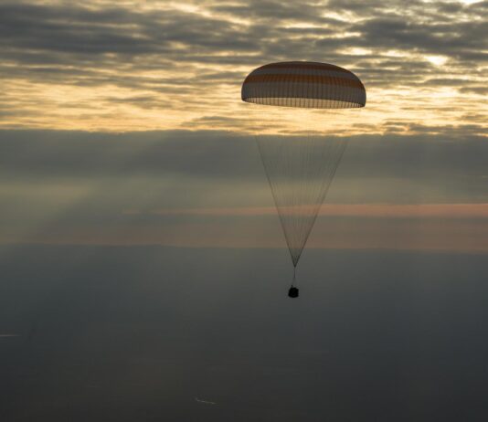 NASA Announces Broadcast for Astronaut Jonny Kim’s Crew Return The photo features a dim horizon with the Soyuz MS-26 spacecraft as it lands by parachute.