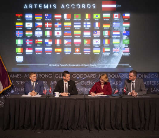Latvia Joins NASA’s Artemis Accords as Newest Signatory Dace Melbārde, Latvia’s Minister for Education and Science, second from right, signs the Artemis Accords, as NASA Administrator Jared Isaacman, second from left, Jacob Helberg, U.S. Under Secretary of State for Economic Affairs, left, and Jānis Beķeris, Chargé D’Affaires a.i. at the Embassy of the Republic of Latvia to the United States, right, look on Monday, April 20, 2026, at the Mary W. Jackson NASA Headquarters building in Washington. The Artemis Accords graphic of all signatory flags is behind them.