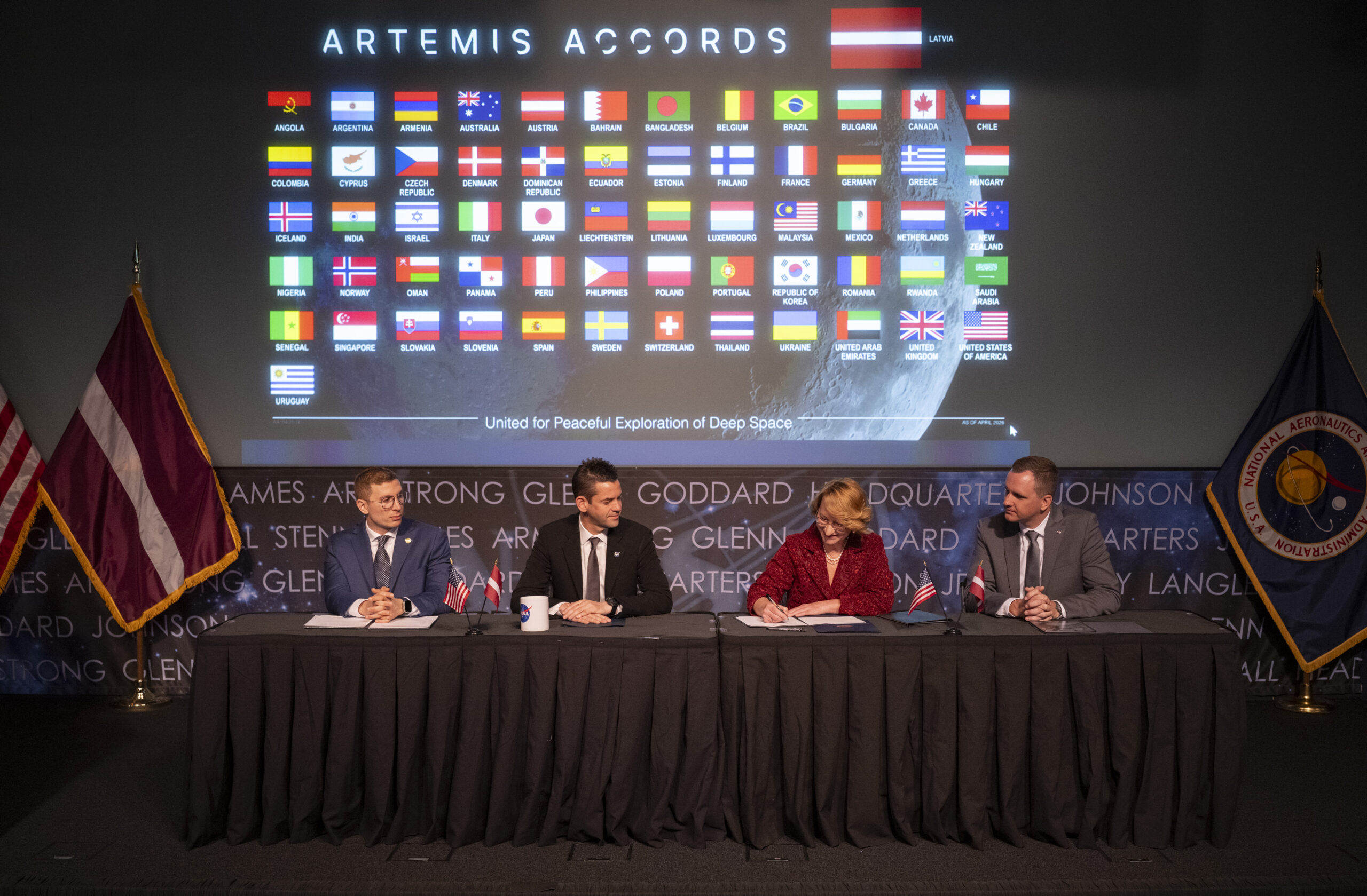 Dace Melbārde, Latvia’s Minister for Education and Science, second from right, signs the Artemis Accords, as NASA Administrator Jared Isaacman, second from left, Jacob Helberg, U.S. Under Secretary of State for Economic Affairs, left, and Jānis Beķeris, Chargé D’Affaires a.i. at the Embassy of the Republic of Latvia to the United States, right, look on Monday, April 20, 2026, at the Mary W. Jackson NASA Headquarters building in Washington. The Artemis Accords graphic of all signatory flags is behind them.