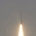 NASA-ISRO Satellite Launched to Monitor Earth’s Surface Changes A large white rocket with a fiery trail launches through a cloudy sky above India.