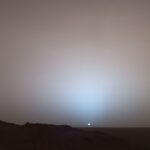 Mars Sunset Captured by NASA The Sun, a small white dot, sets in this photo from Mars. The sky is dusty and slightly red.