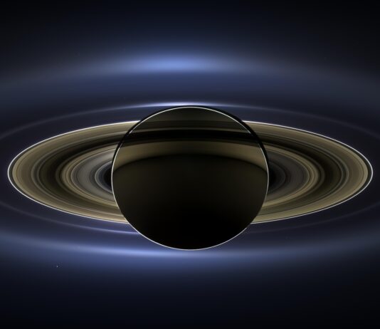 NASA Captures Earth’s Smile from Space Saturn is a dark sphere with a bright outline. Its outermost rings are fuzzy and blue. The rings get crisper as you go inward toward the planet. These inner rings are yellow. Earth is a tiny speck of light in the background on the lower right, between the bright blue E ring and the faint but defined G ring.