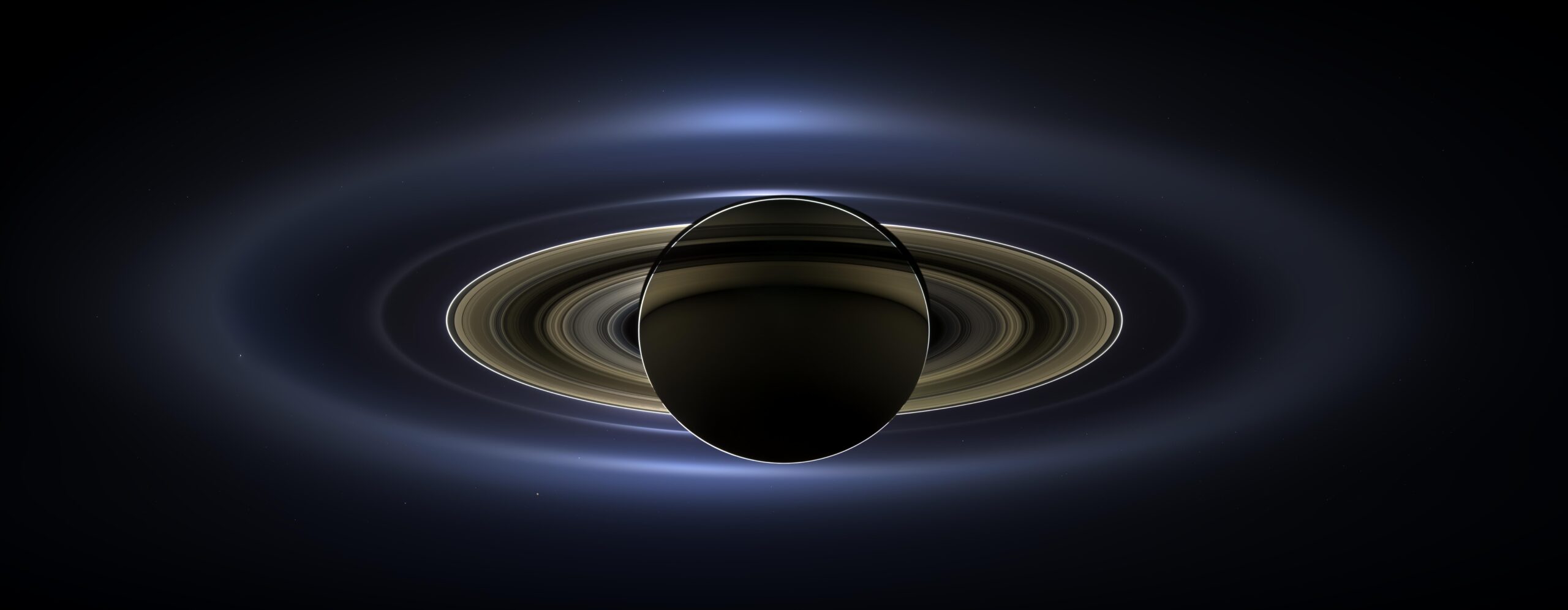 pia17172orig.jpg Saturn is a dark sphere with a bright outline. Its outermost rings are fuzzy and blue. The rings get crisper as you go inward toward the planet. These inner rings are yellow. Earth is a tiny speck of light in the background on the lower right, between the bright blue E ring and the faint but defined G ring.