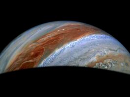 NASA Explores Jupiter’s Chaotic Atmospheric Conditions Part of Jupiter is visible in this image. Its iconic belts and zones stand out in rusty red and blue, along with turbulent activity on their edges.