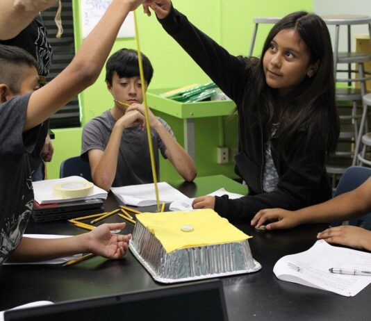 NASA Unveils Free PLANETS Resources for After-School Programs An out of school time educator holds a measuring tape as an elementary aged girl drops a weight to test the space craft shield her group created. Her group members, two boys and one girl, watch as she drops the weight.