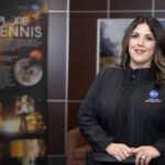 NASA Stennis Celebrates Employee’s Achievement Rebecca Mataya stands for a portrait wearing a black jacket; Stennis posters are shown in the background