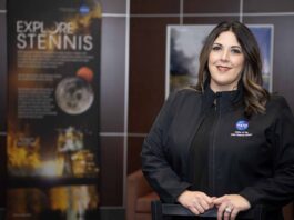 NASA Stennis Celebrates Employee’s Achievement Rebecca Mataya stands for a portrait wearing a black jacket; Stennis posters are shown in the background