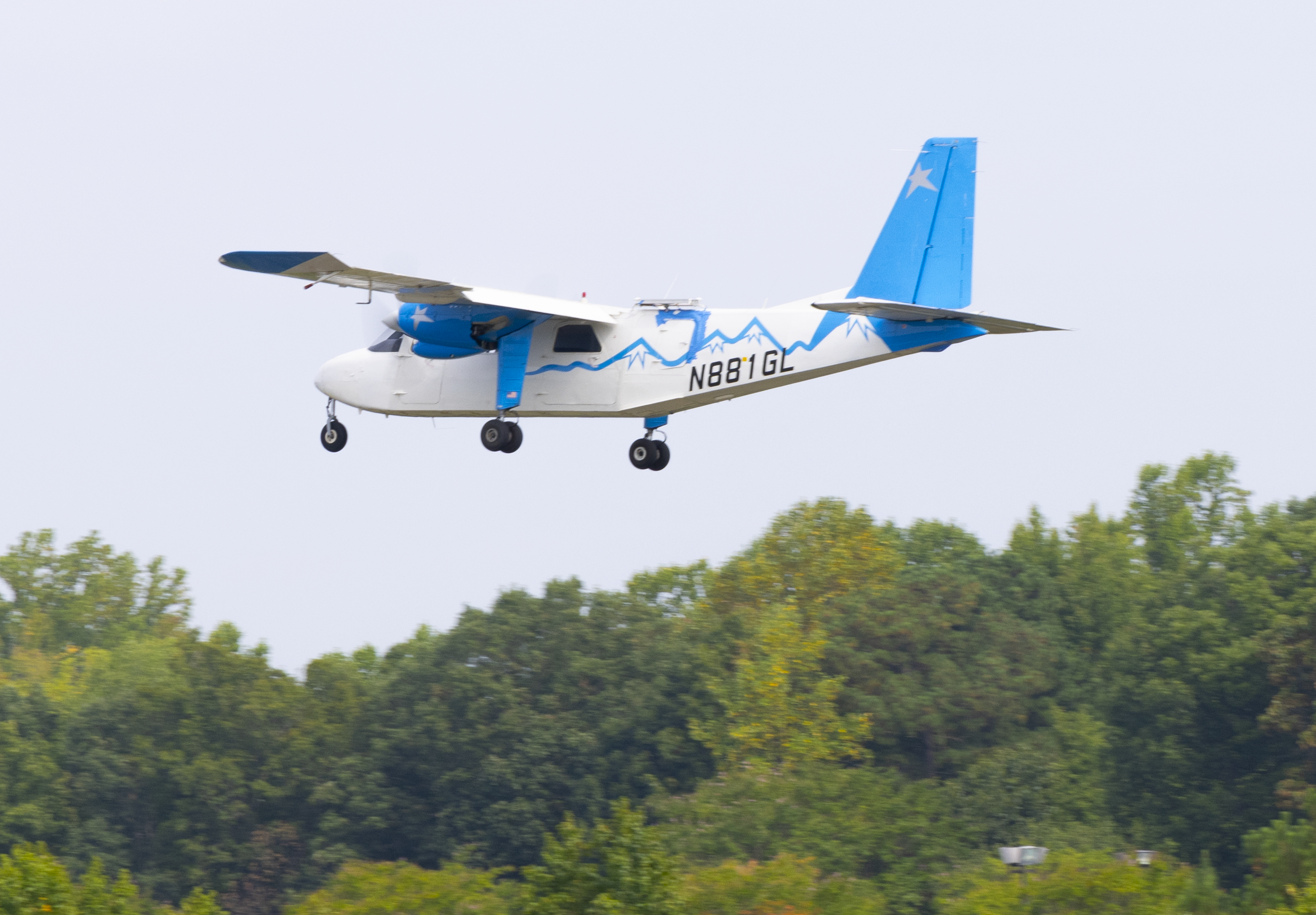 rped aerogel 2024 0739 eb1d05.png A white-and-blue Britten-Norman Defender aircraft outfitted for a flight test with an advanced phased array antenna prototype. The array is mounted on top of the fuselage near the center of the airplane. The plane is seen in flight over trees.