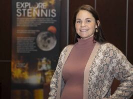 Heather Seagren Streamlines Travel for NASA Staff Heather Seagren pauses for a photo in front of an Explore Stennis poster