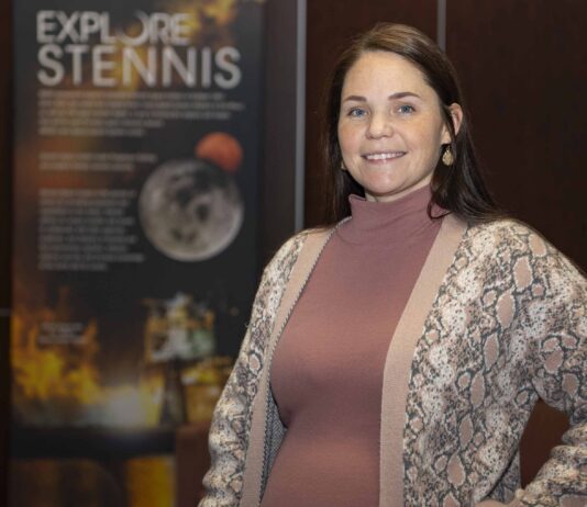 Heather Seagren Streamlines Travel for NASA Staff Heather Seagren pauses for a photo in front of an Explore Stennis poster