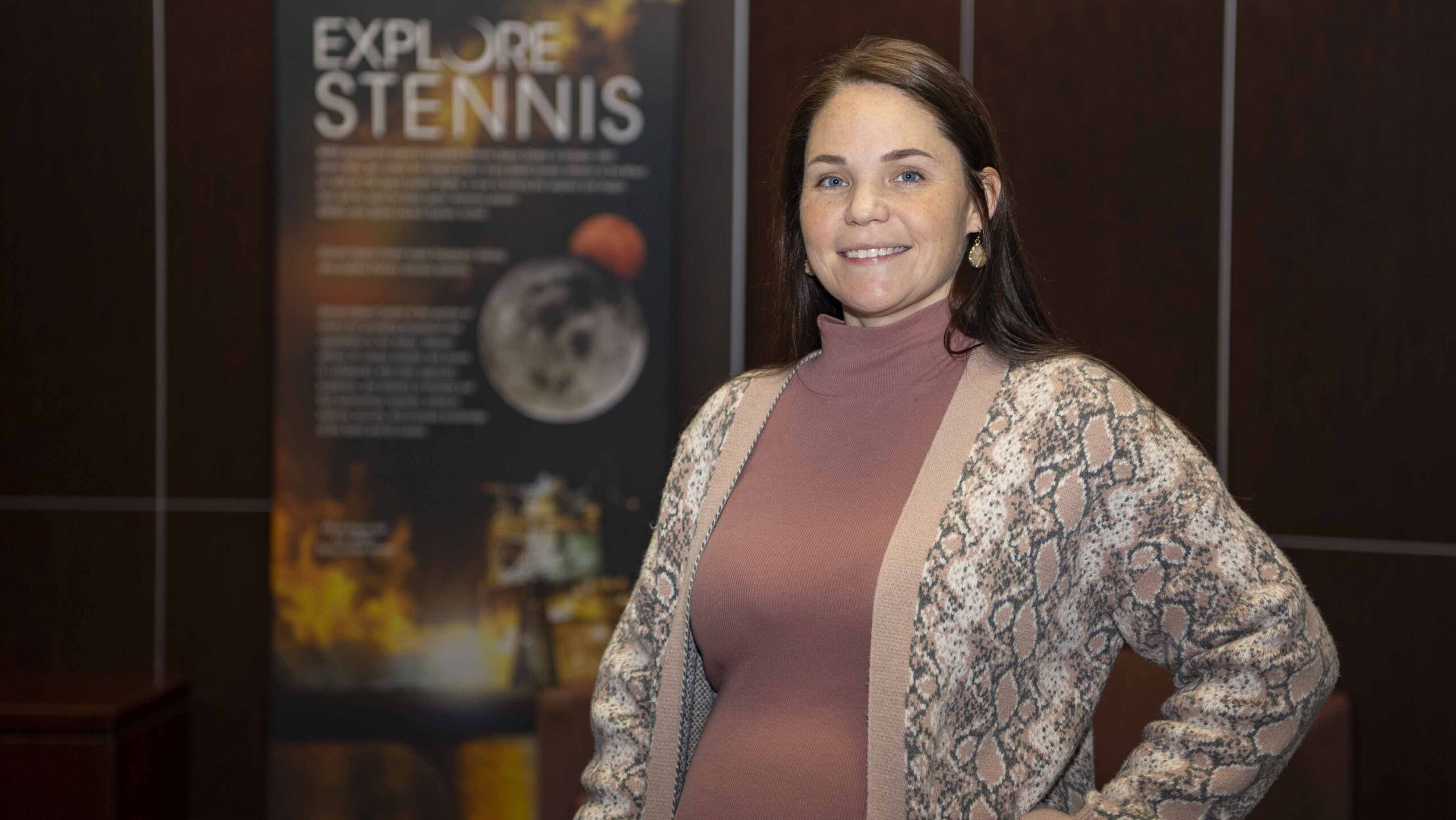 s25 001 heather seagren e1735836147165.jpg Heather Seagren pauses for a photo in front of an Explore Stennis poster