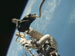 NASA Conducts America’s Inaugural Spacewalk Mission An astronaut in a spacesuit floats almost upside down outside of a spacecraft. Earth