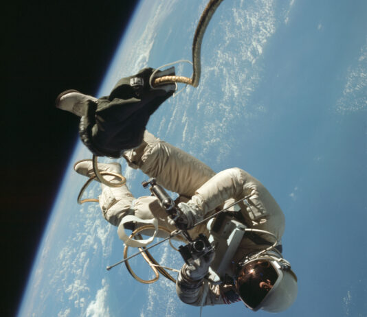 NASA Conducts America’s Inaugural Spacewalk Mission An astronaut in a spacesuit floats almost upside down outside of a spacecraft. Earth