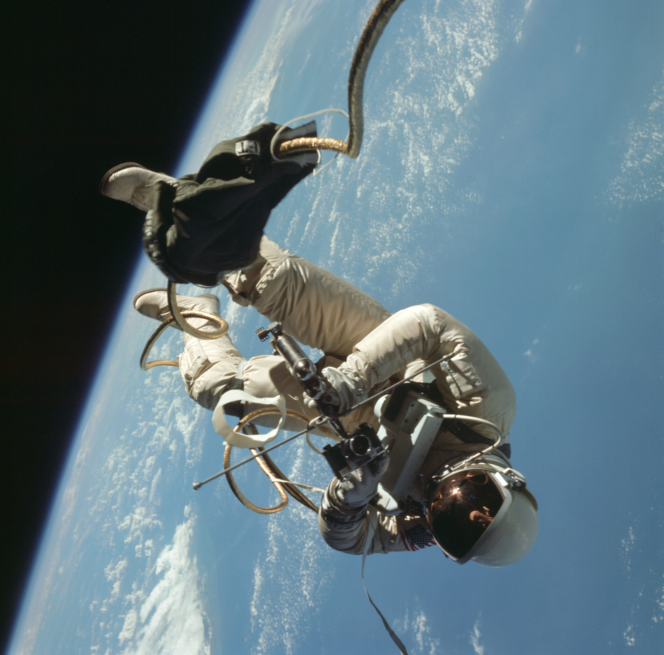 s65 30432orig.jpg An astronaut in a spacesuit floats almost upside down outside of a spacecraft. Earth