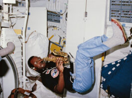 NASA’s Space Mission Features Saxophone Performance A Black man plays a saxophone while floating. He wears a black short sleeve shirt with patches on it, blue pants, and gray shoes. He is inside the space shuttle Challenger.