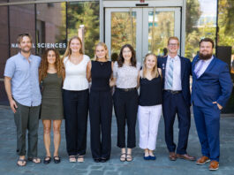 NASA’s SARP West 2024: Oceans Group Exploration A group of eight people. the first a professor and the other seven college age, stand in a line in professional attire. Behind them is a glass building with glass doors, reflecting green trees.