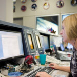 Erin Sholl’s Unforeseen Journey to NASA Spaceflight Safety A woman sits in front of a bank of computer screens in the Mission Control Center at Johnson Space Center.