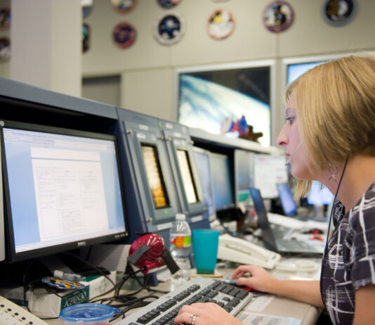 Erin Sholl’s Unforeseen Journey to NASA Spaceflight Safety A woman sits in front of a bank of computer screens in the Mission Control Center at Johnson Space Center.