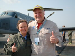 NASA’s Bob Swap Fosters Connections Through Science Diplomacy Woman wearing a green jacket and man wearing a tan button down shirt with the Goddard logo stand on a runway in front of a plane.