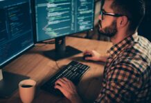 Monitoring Server Load in Linux: A Comprehensive Guide Programmer coding on dual monitors at night.