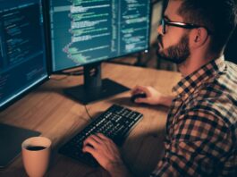Monitoring Server Load in Linux: A Comprehensive Guide Programmer coding on dual monitors at night.