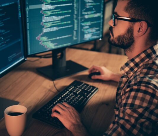 Monitoring Server Load in Linux: A Comprehensive Guide Programmer coding on dual monitors at night.