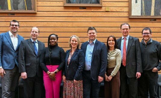 Lenovo and University of Southampton Collaborate on High-Performance Computing A line of men and women in business smiling at the camera in front of a wooden background