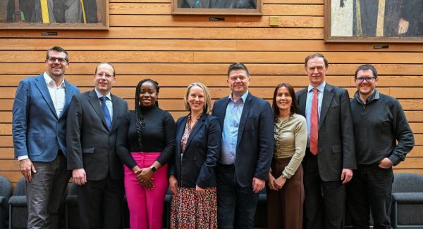 university of southampton lenovo hpc 600x326.jpg A line of men and women in business smiling at the camera in front of a wooden background