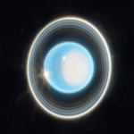Oxford and NASA Find Uranus Warmer Than Previously Believed A glowing, bright blue-white circular sphere in the center of the image, surrounded by multiple concentric, thin rings of varying brightness against a black background. The rings appear as gray, white, and light-colored bands encircling the central blue-white disc. The outer ring appears brighter than the inner rings, with subtle variations in thickness and illumination throughout the ring structure.