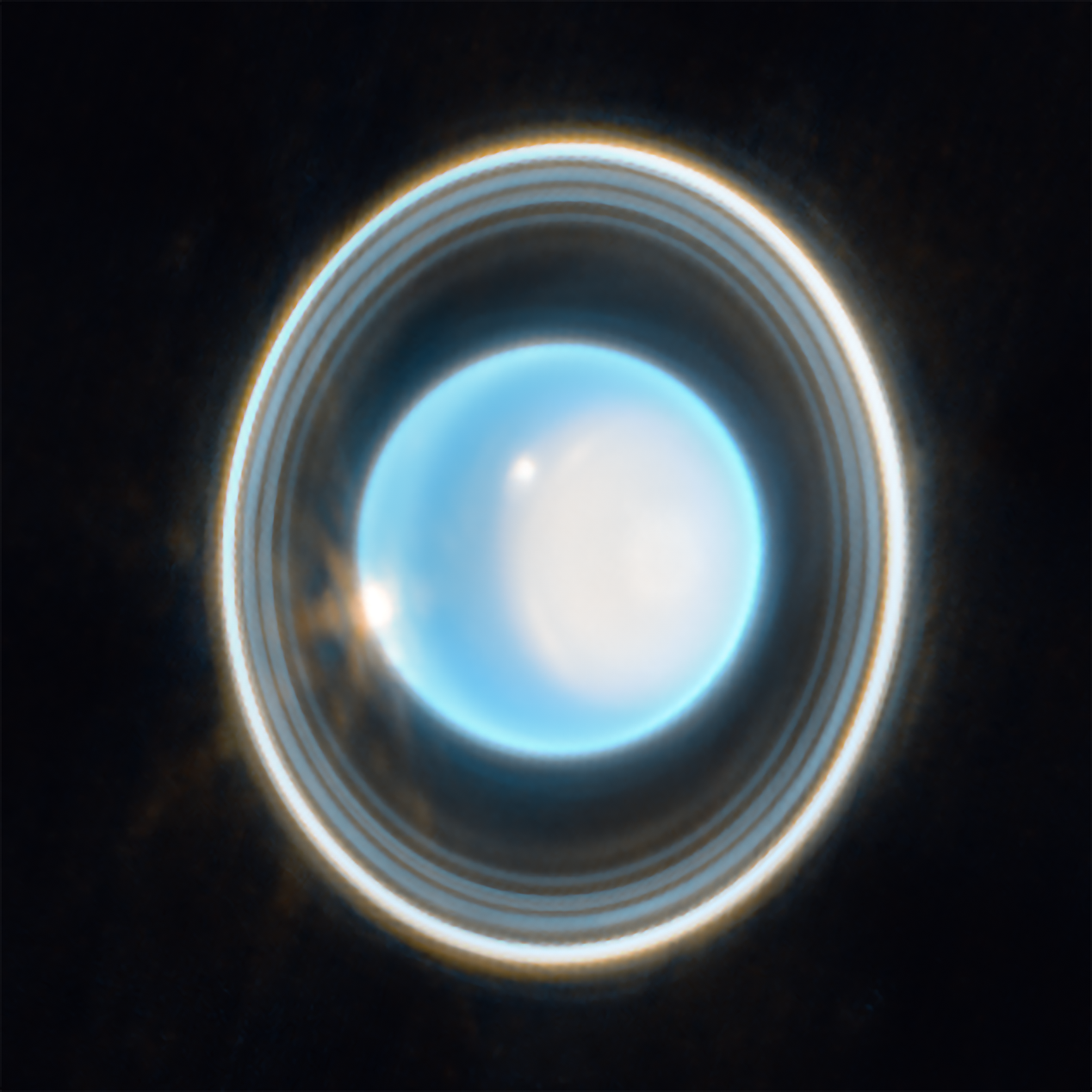 uranusmain.png A glowing, bright blue-white circular sphere in the center of the image, surrounded by multiple concentric, thin rings of varying brightness against a black background. The rings appear as gray, white, and light-colored bands encircling the central blue-white disc. The outer ring appears brighter than the inner rings, with subtle variations in thickness and illumination throughout the ring structure.