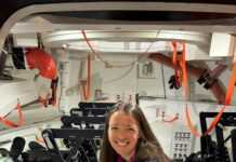 Branelle Rodriguez Prepares Orion for Artemis II Launch – NASA A woman crouches inside the mockup of a spacecraft that is equipped with seats for crewmembers.