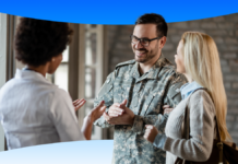 VHA Implements Salesforce OS, Boosting Veteran Care Efficiency. Smiling man in army fatigues discussing care options with woman.